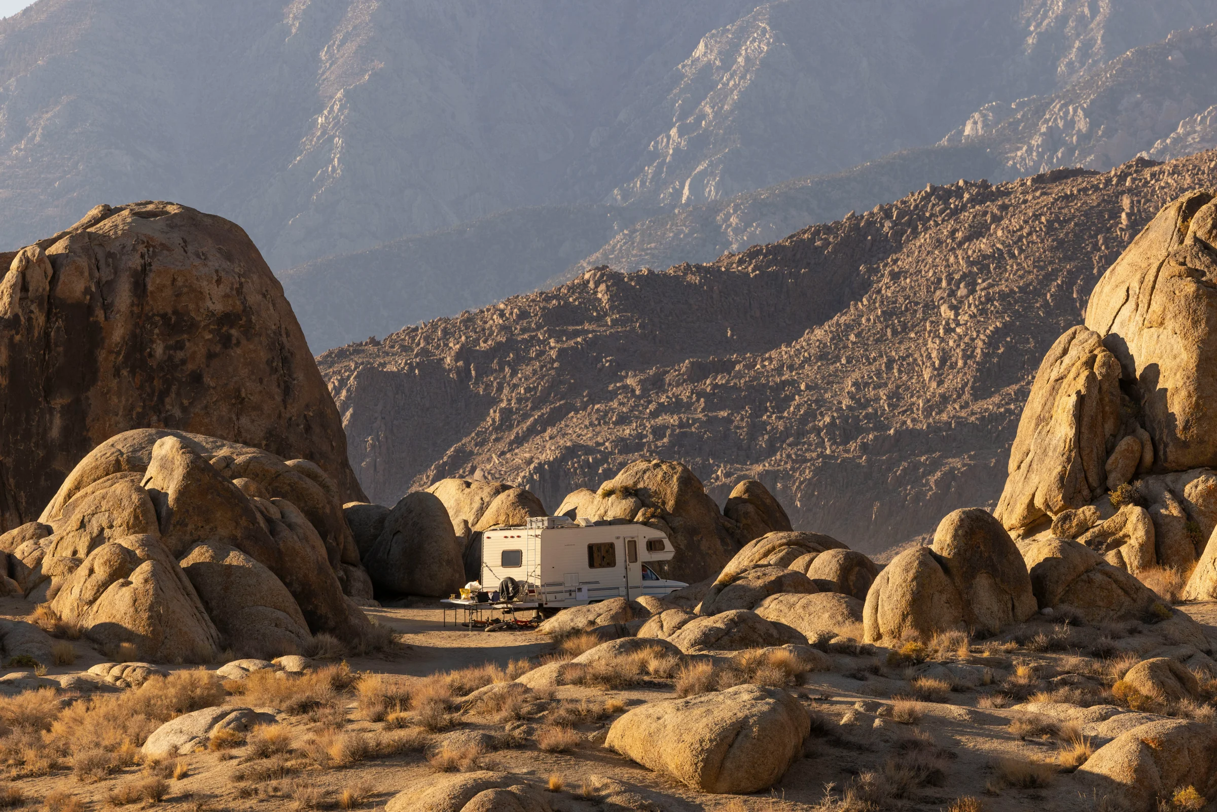 A motorhome tucked among sunlit boulders in California’s Alabama Hills.